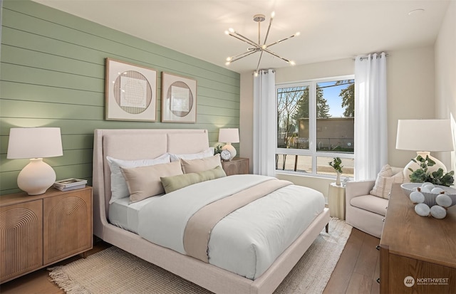 bedroom with a notable chandelier, wooden walls, and hardwood / wood-style floors