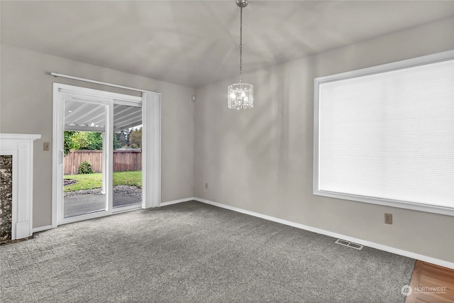 carpeted empty room featuring a notable chandelier