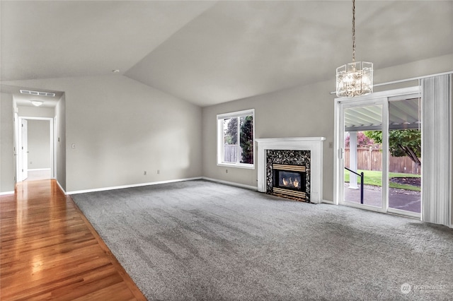 unfurnished living room with lofted ceiling, a chandelier, wood-type flooring, and a fireplace