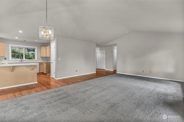 unfurnished living room featuring light hardwood / wood-style floors, lofted ceiling, a chandelier, and sink