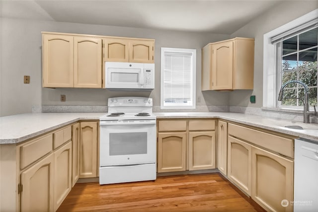 kitchen featuring kitchen peninsula, light brown cabinetry, light hardwood / wood-style floors, sink, and white appliances