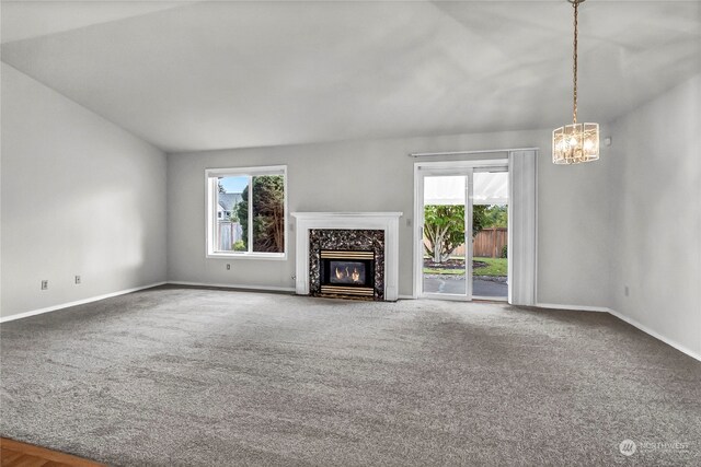 unfurnished living room featuring a high end fireplace, a healthy amount of sunlight, carpet, and vaulted ceiling