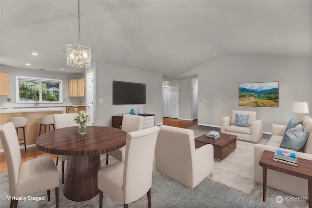 living room with light hardwood / wood-style floors, a notable chandelier, sink, and vaulted ceiling