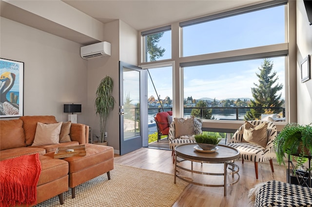 living room with light hardwood / wood-style floors, a water view, and a wall mounted AC