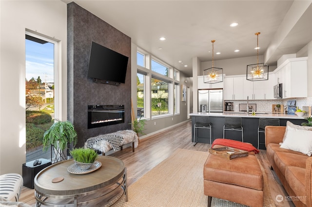 living room with light wood-type flooring, a fireplace, and sink