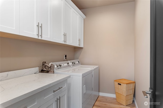 laundry room with light wood-type flooring, cabinets, and washing machine and clothes dryer