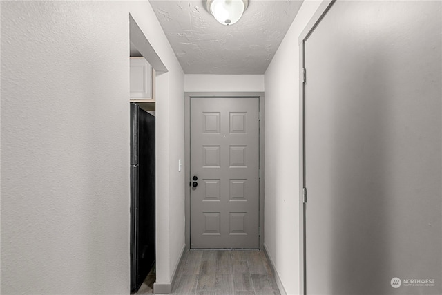 hall featuring light hardwood / wood-style floors and a textured ceiling