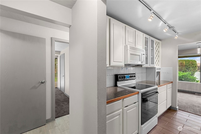 kitchen with white appliances, light hardwood / wood-style flooring, backsplash, rail lighting, and white cabinetry