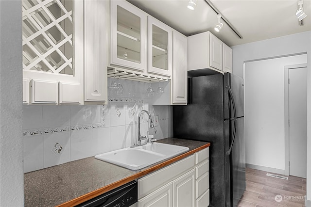 kitchen with black fridge, sink, tasteful backsplash, light hardwood / wood-style flooring, and white cabinetry