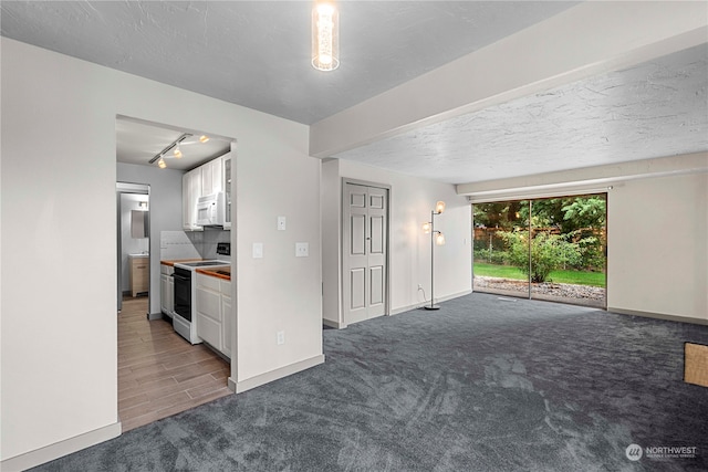 interior space featuring rail lighting, white appliances, white cabinetry, dark carpet, and a textured ceiling