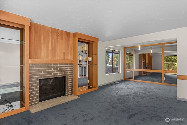 unfurnished living room featuring dark carpet and a brick fireplace