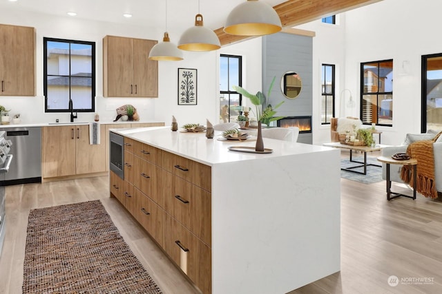 kitchen featuring light hardwood / wood-style floors, hanging light fixtures, a large fireplace, and a kitchen island