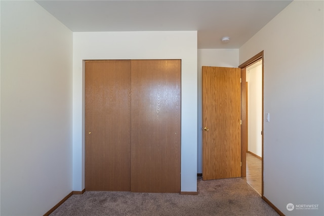 unfurnished bedroom with light carpet and a closet