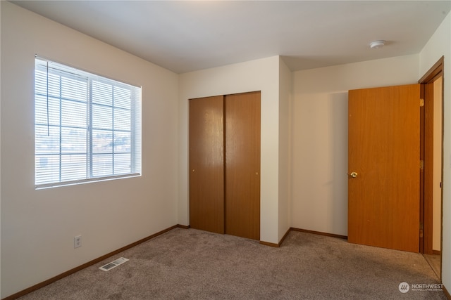 unfurnished bedroom featuring light colored carpet and a closet