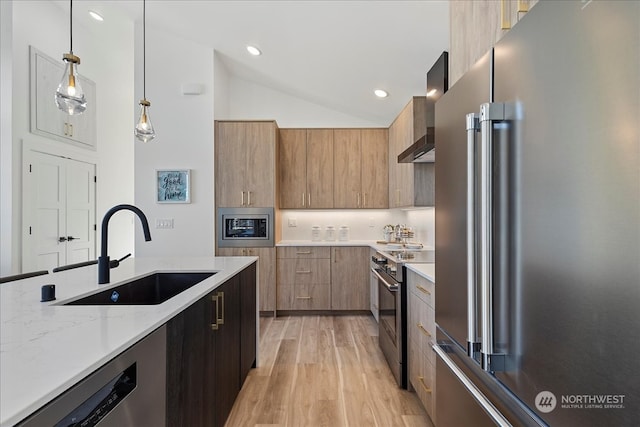 kitchen with lofted ceiling, light stone counters, stainless steel appliances, sink, and pendant lighting