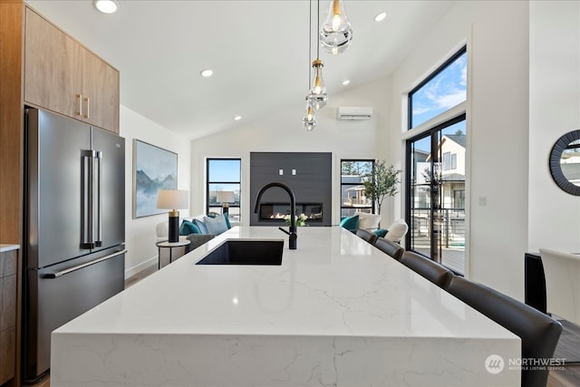 kitchen featuring pendant lighting, light stone countertops, high quality fridge, and lofted ceiling