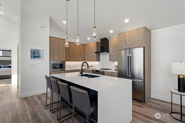 kitchen with vaulted ceiling, a kitchen island with sink, wall chimney exhaust hood, stainless steel appliances, and a kitchen bar