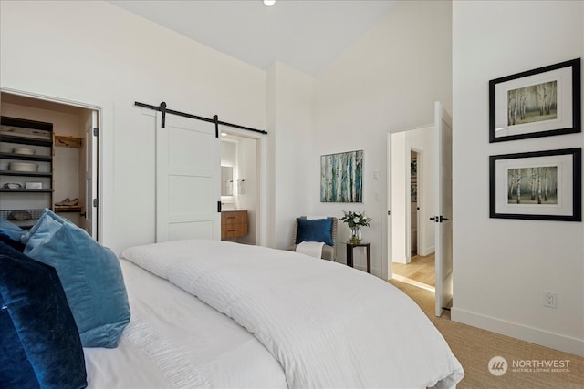 bedroom featuring high vaulted ceiling, a closet, ensuite bath, a barn door, and light colored carpet