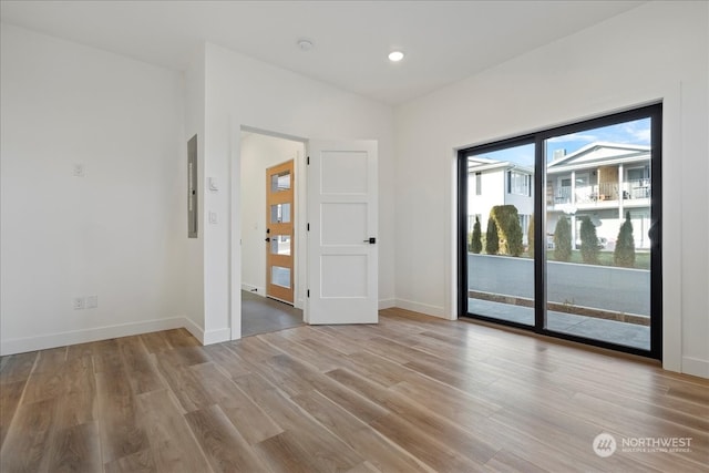 empty room featuring electric panel and light hardwood / wood-style floors