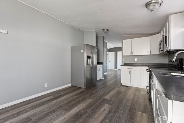 kitchen with white cabinets, lofted ceiling, sink, dark wood-type flooring, and stainless steel appliances