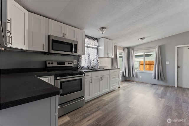 kitchen featuring dark wood-type flooring, sink, stainless steel appliances, and white cabinets