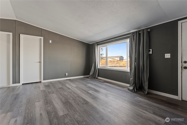 spare room featuring lofted ceiling, hardwood / wood-style floors, and a textured ceiling