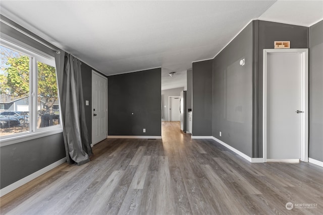 spare room with wood-type flooring and lofted ceiling