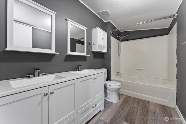 full bathroom featuring tub / shower combination, toilet, wood-type flooring, vanity, and a textured ceiling