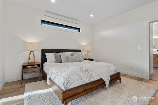 bedroom featuring connected bathroom and light wood-type flooring