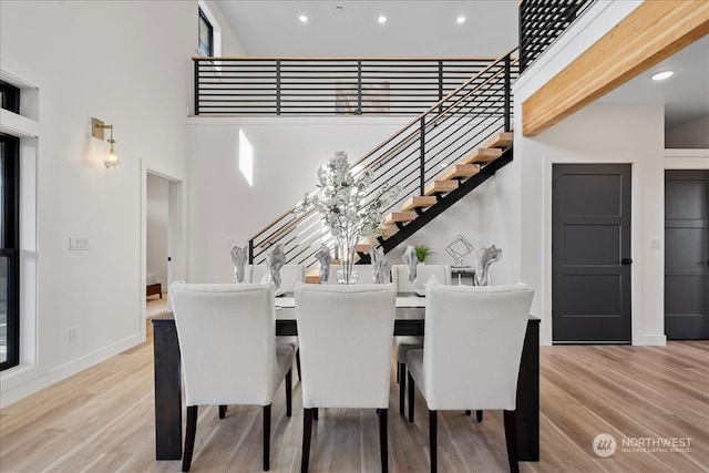 dining area with a towering ceiling and light wood-type flooring