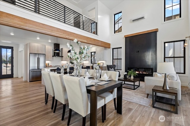 dining area with a high ceiling, a fireplace, and light hardwood / wood-style flooring