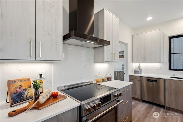 kitchen with dark hardwood / wood-style flooring, wall chimney range hood, gray cabinets, and stainless steel appliances