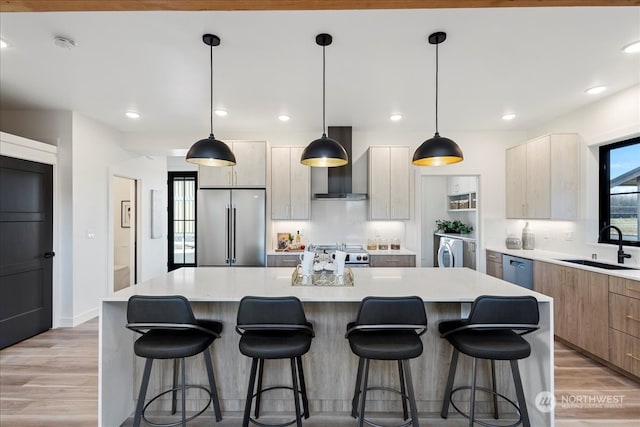 kitchen featuring stainless steel appliances, pendant lighting, a center island, and wall chimney range hood