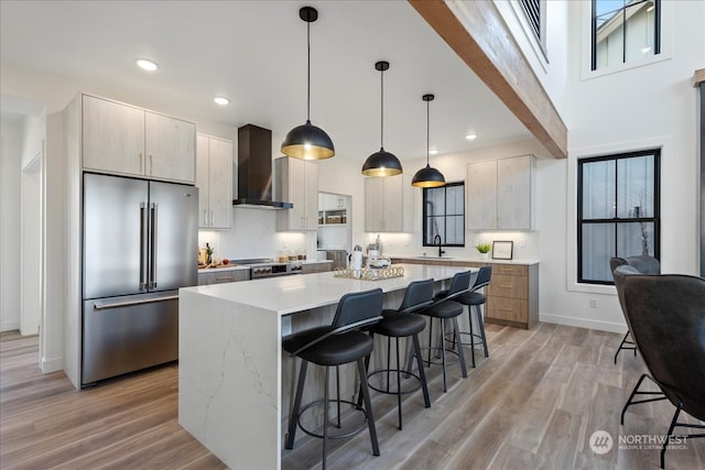 kitchen featuring decorative light fixtures, a kitchen island, wall chimney exhaust hood, and appliances with stainless steel finishes