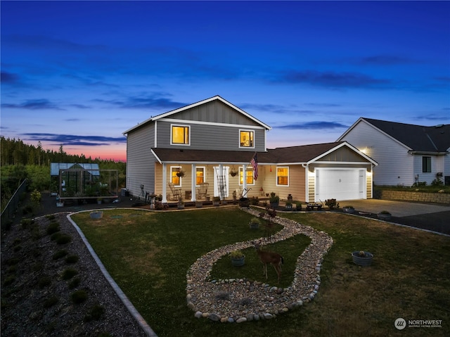 view of front of home featuring a yard, a porch, and a garage