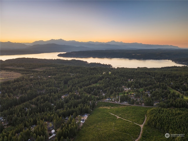 aerial view at dusk featuring a water and mountain view