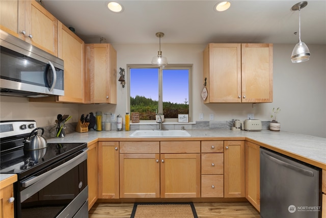 kitchen featuring light hardwood / wood-style floors, stainless steel appliances, sink, and pendant lighting