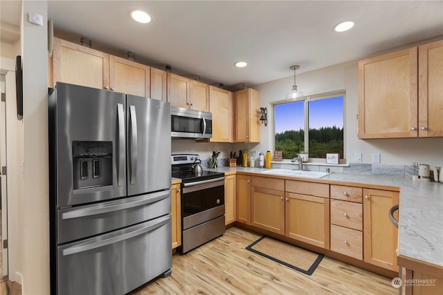 kitchen featuring sink, pendant lighting, light brown cabinetry, appliances with stainless steel finishes, and light hardwood / wood-style floors