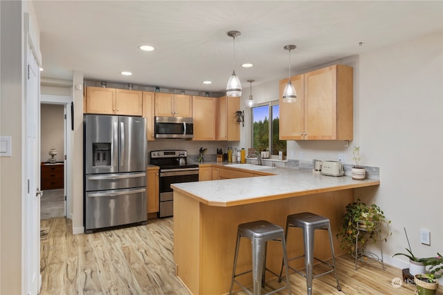 kitchen with light brown cabinetry, kitchen peninsula, a kitchen breakfast bar, light hardwood / wood-style floors, and stainless steel appliances