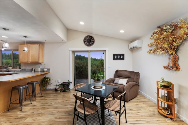 dining area featuring sink, vaulted ceiling, a wall mounted AC, and light hardwood / wood-style floors
