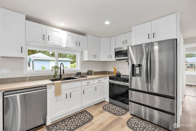 kitchen featuring appliances with stainless steel finishes, a wealth of natural light, sink, and white cabinets