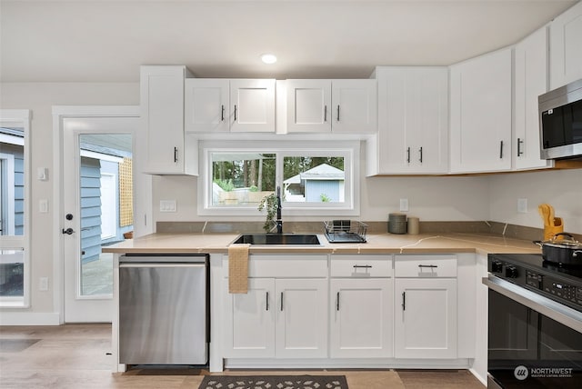 kitchen featuring light hardwood / wood-style flooring, appliances with stainless steel finishes, sink, and white cabinetry