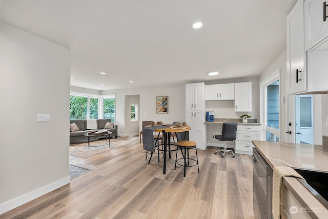 kitchen with light hardwood / wood-style floors, white cabinets, and a kitchen breakfast bar