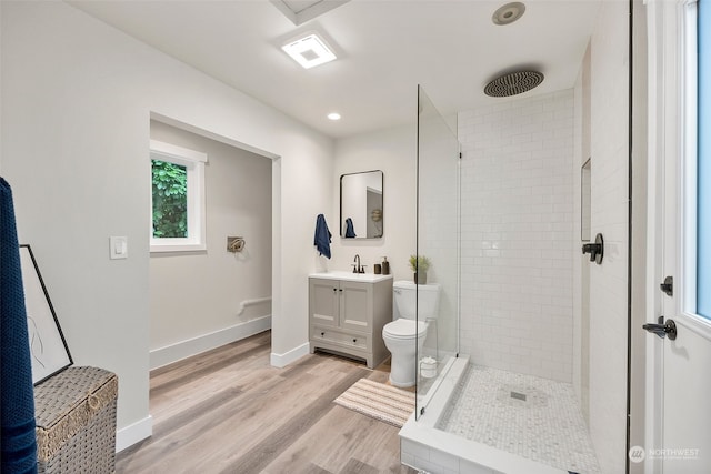 bathroom featuring a tile shower, vanity, toilet, and hardwood / wood-style flooring