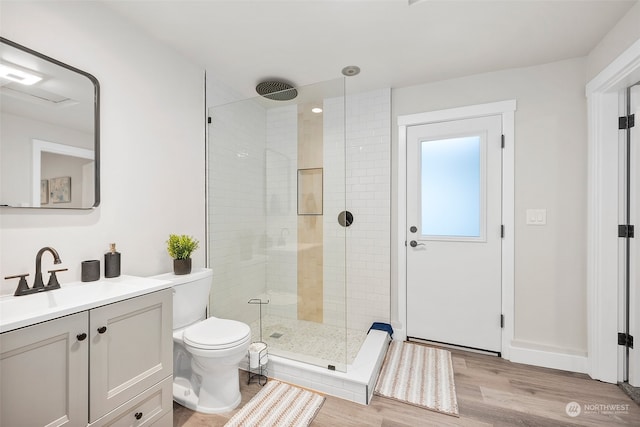 bathroom featuring hardwood / wood-style floors, a shower with shower door, vanity, and toilet