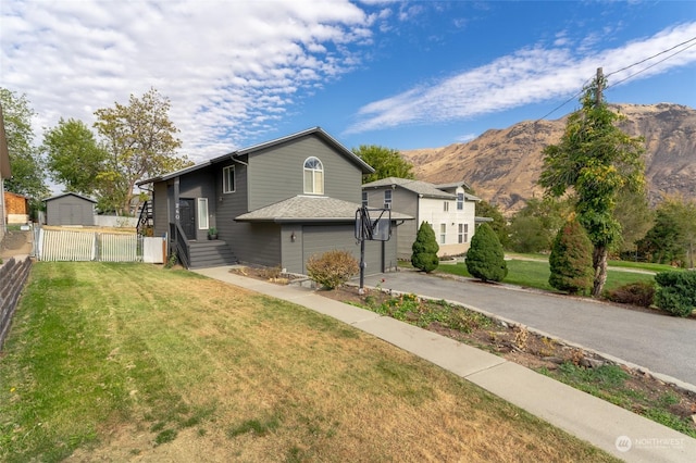 260 Chestnut St, Chelan Falls, WA 98817 - bi-level home featuring driveway, an attached garage, fence, a mountain view, and a front yard