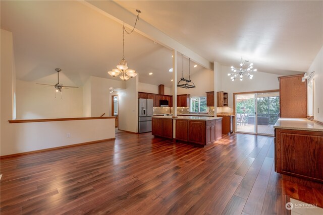 kitchen with hanging light fixtures, a kitchen island, dark wood-type flooring, high vaulted ceiling, and stainless steel appliances