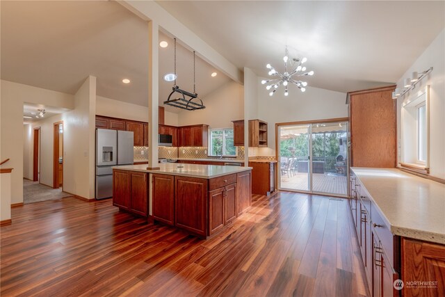 kitchen with a kitchen island, dark hardwood / wood-style floors, fridge with ice dispenser, a notable chandelier, and pendant lighting