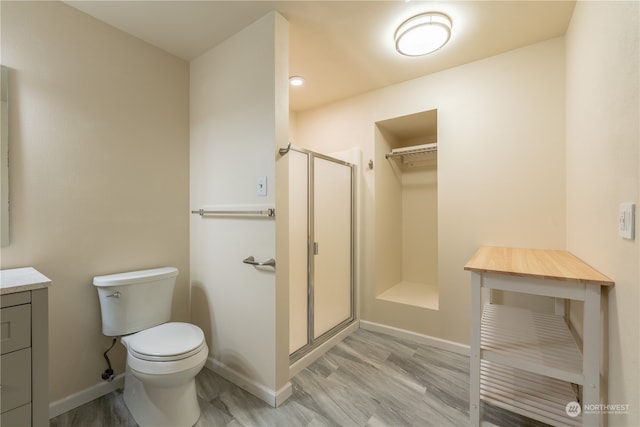 bathroom with toilet, a shower with door, vanity, and wood-type flooring