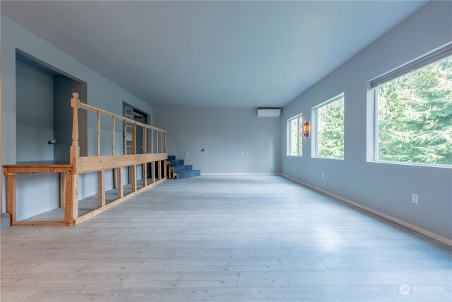 spare room with a wall unit AC and light hardwood / wood-style flooring